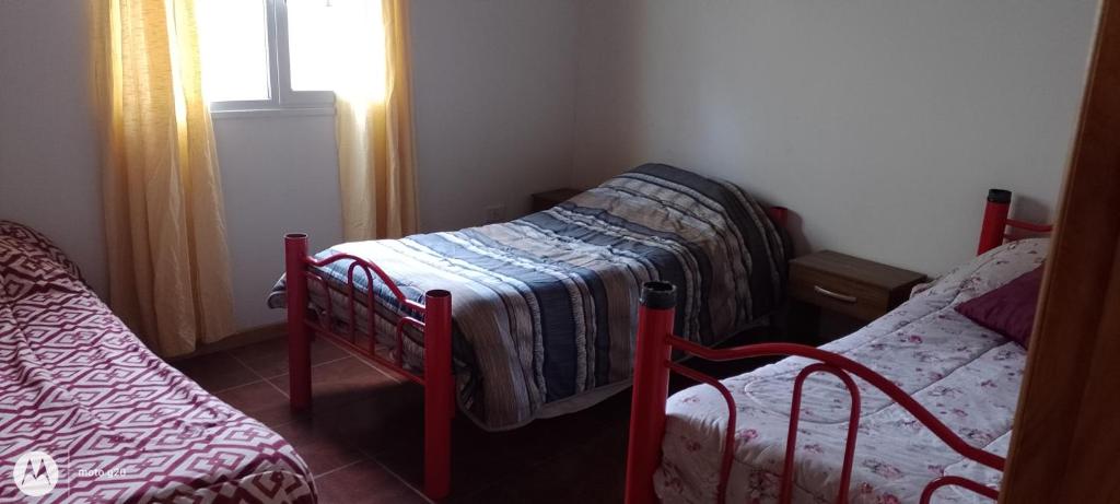 two twin beds in a room with a window at El cahuquen casa 2 dormitorios in Junín de los Andes