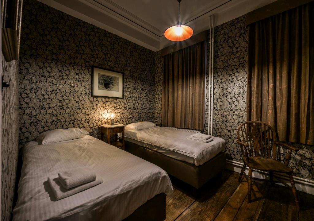pokój hotelowy z 2 łóżkami, stołem i krzesłami w obiekcie Talbot House w mieście Poperinge