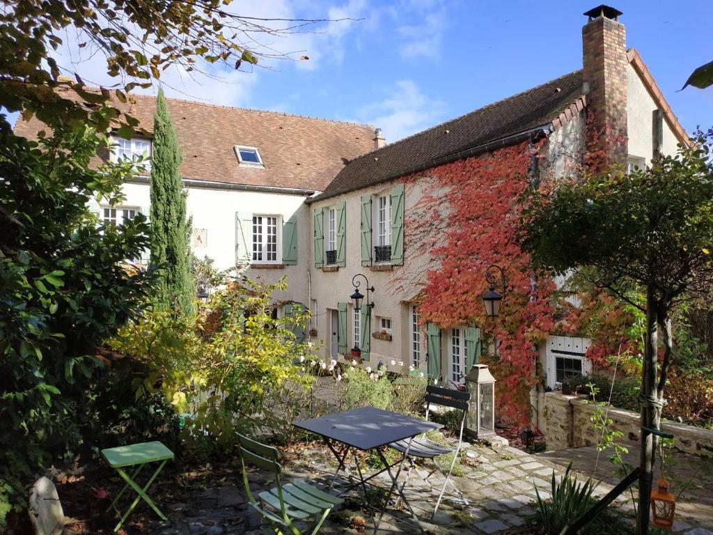 une maison avec un jardin en face dans l'établissement Maison d'hôtes La Source, à Magny-les-Hameaux