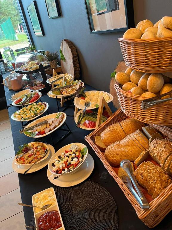 a table with plates of food and baskets of bread at Hotel Galion in Gdańsk