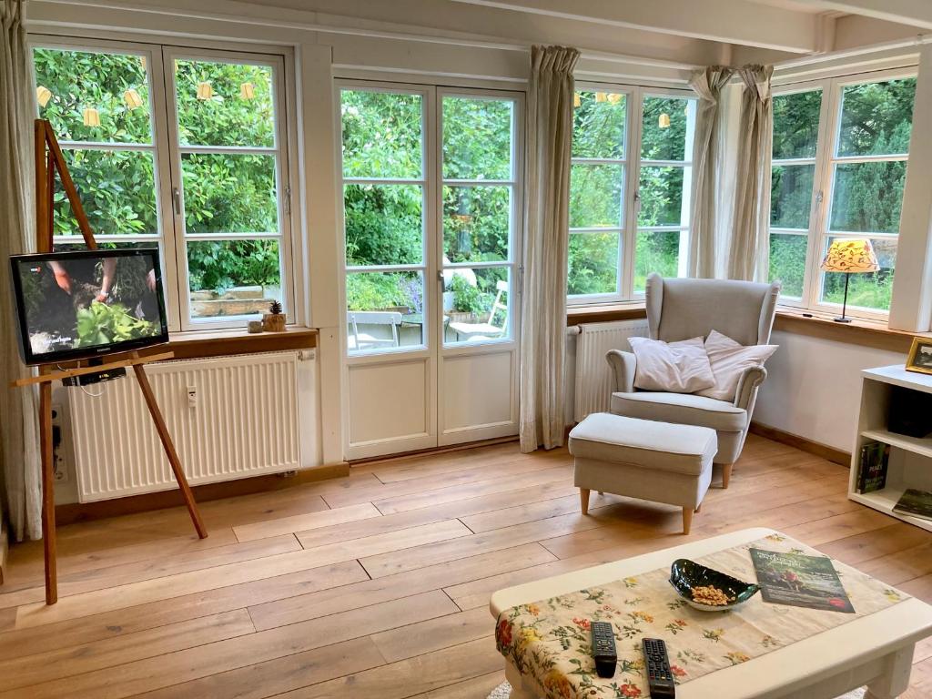 uma sala de estar com janelas, uma televisão e uma cadeira em Ökologisches und modernes Waldhäuschen em Solingen