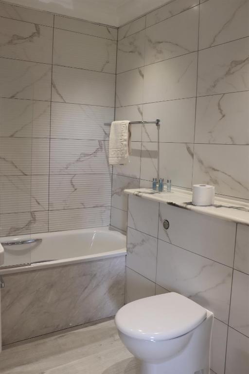 a white bathroom with a toilet and a bath tub at Portclew House in Pembroke