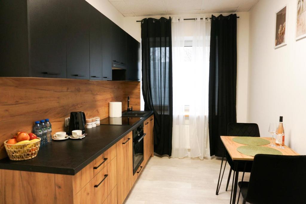a kitchen with a black counter top and a table at Nowoczesny Apartament Prudnik in Prudnik