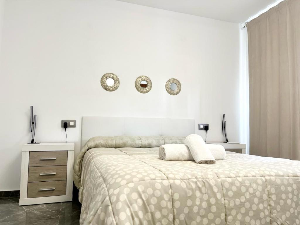 a white bedroom with a bed and two mirrors on the wall at Apartamento Alteagroup Centro in Altea