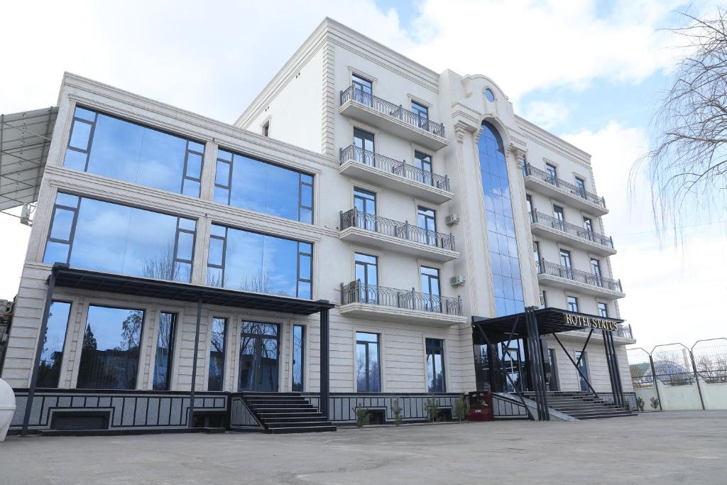a large white building with a lot of windows at STATUS HOTEL in Qarshi