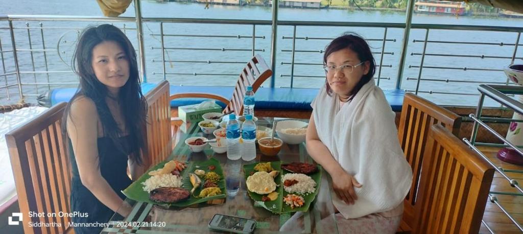 Um homem e uma mulher sentados à mesa com comida. em Beach Paradise Day Cruise Houseboat - VACCINATED STAFF em Alappuzha