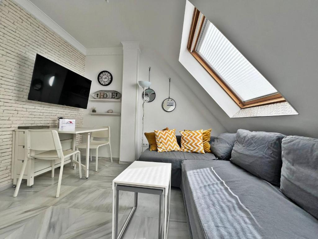 Una sala de estar con un sofá gris y una mesa. en Coqueto ático de playa, en Fuengirola