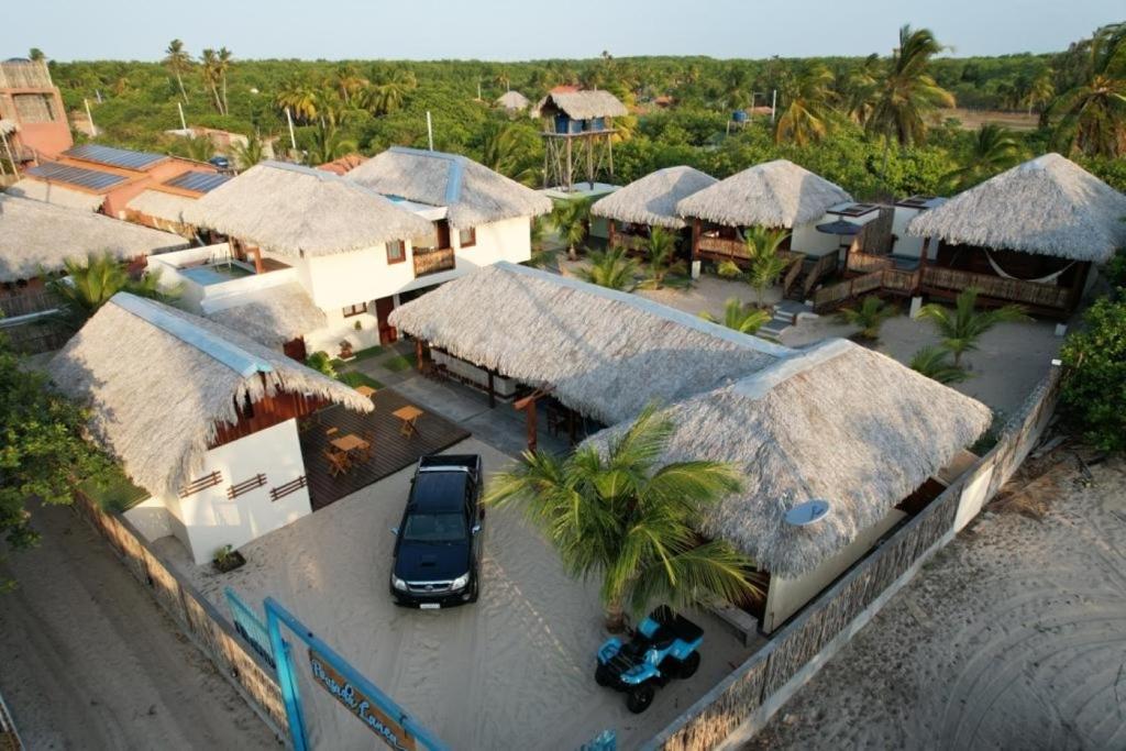 a car parked in front of a house with thatched roofs at Pousada Lanea Experience in Atins