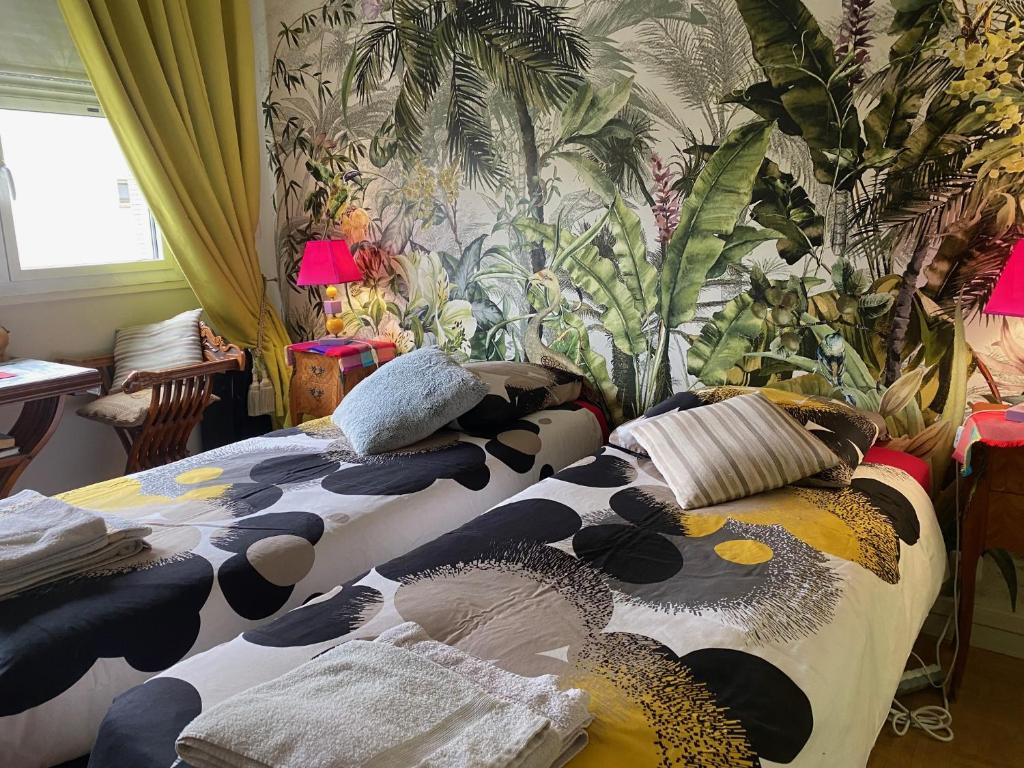 two beds in a room with a wall with plants at L'Etoile du Sud in Tours