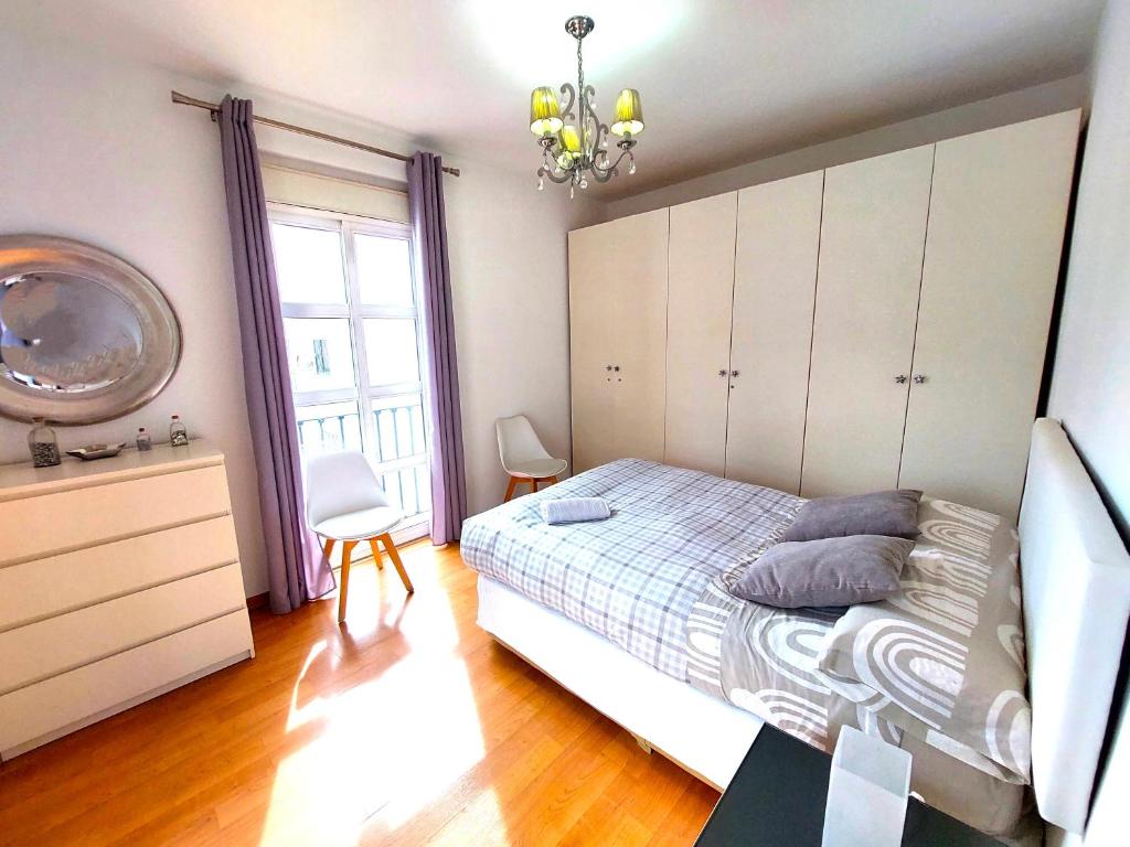 sypialnia z łóżkiem i żyrandolem w obiekcie Maravilla Apartment w Sewilli