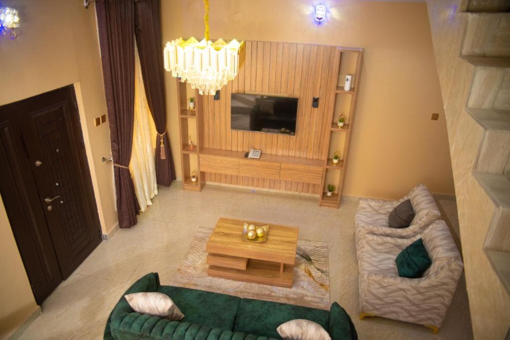 uma sala de estar com um sofá verde e uma mesa em Enny'scourt Service Apartment em Akure