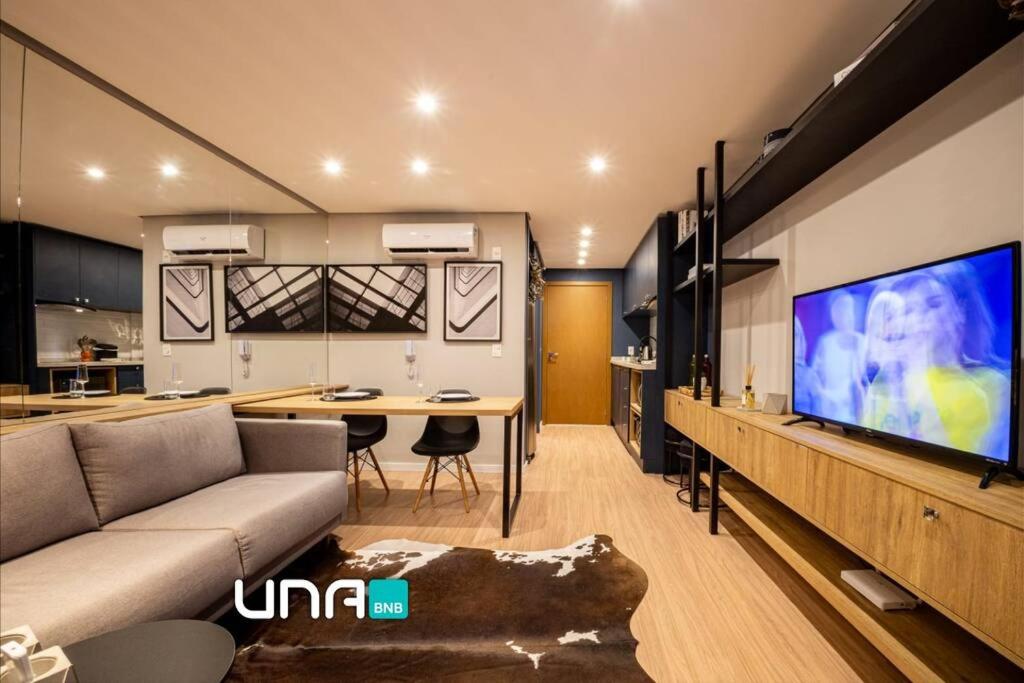 a living room with a couch and a large screen tv at Loft 406 Parque Una + garagem in Pelotas