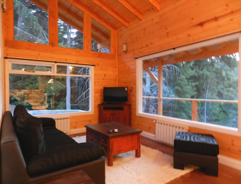 ein Wohnzimmer mit einem Sofa, einem TV und 2 Fenstern in der Unterkunft Ayelen Cabañas in Villa La Angostura