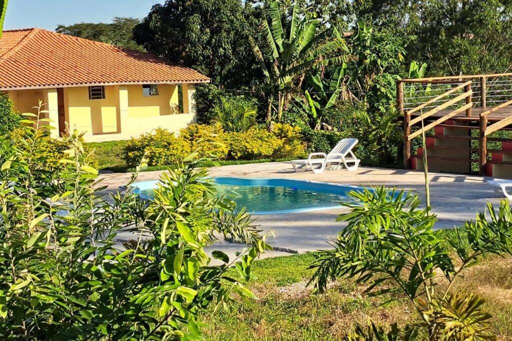 una piscina con una silla junto a una casa en Casa em sítio à beira do Rio Piracicaba c/ piscina en São Pedro