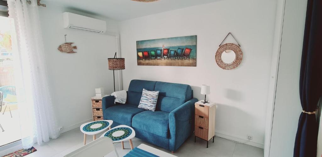 uma sala de estar com um sofá azul e um quadro em Studio port et mer em Le Grau-du-Roi