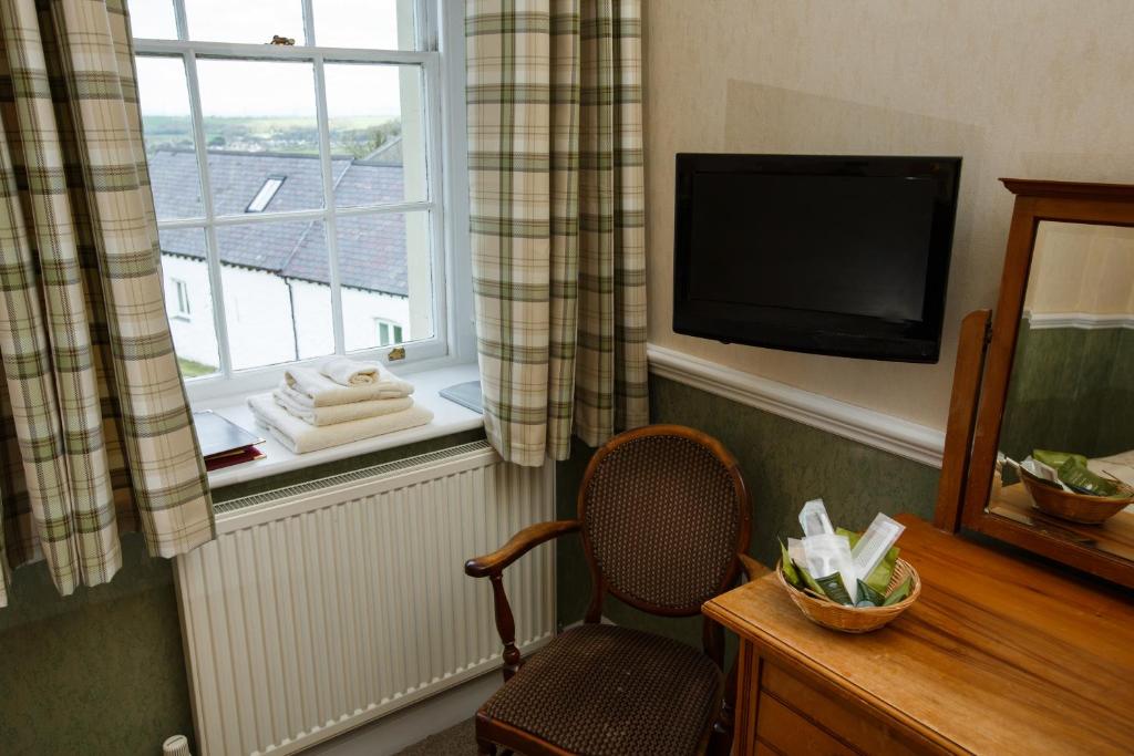 a room with a chair and a television and a window at Portclew House in Pembroke