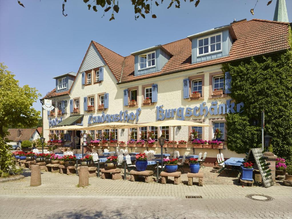 ein Gebäude mit Tischen und Stühlen davor in der Unterkunft Hotel & Restaurant Burgschänke in Kaiserslautern