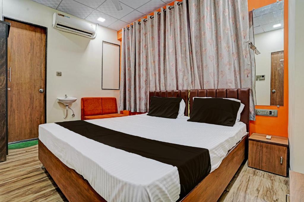 a hotel room with a bed and a chair at Super OYO Hotel Orange in Surat