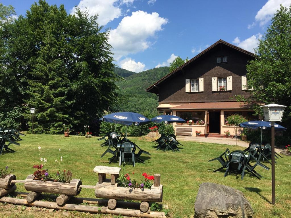 a house with a yard with tables and umbrellas at Le Chalet in Luttenbach-près-Munster