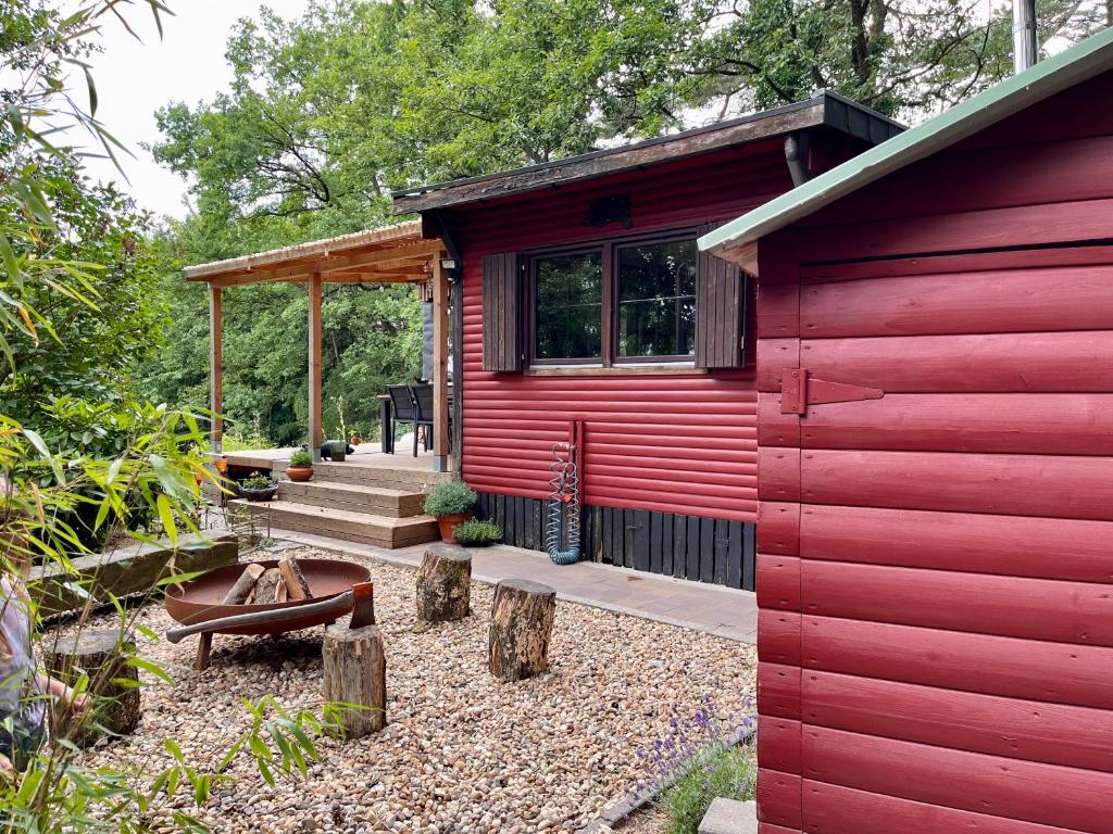 a red cabin with a bench and a patio at Woods House in La Calamine