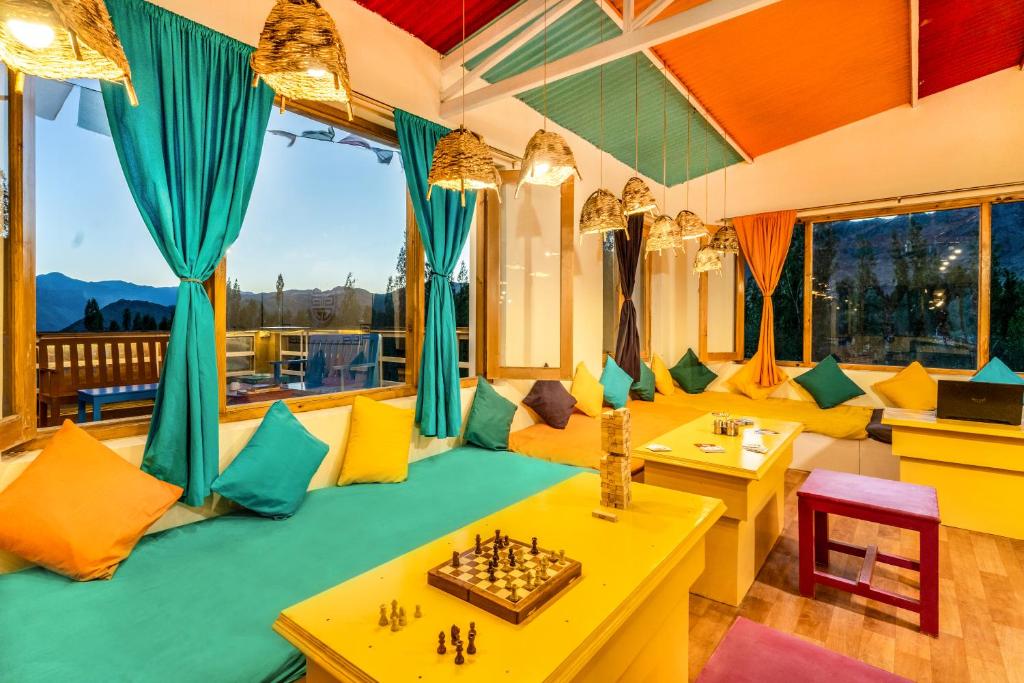 Downtown Hostel Leh في ليه: غرفة معيشة واثاث اصفر واخضر ورقعة شطرنج