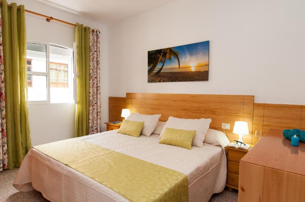 Apartamentos Kasa في لاس بالماس دي غران كاناريا: غرفة نوم بسرير كبير ومصبغتين ونافذة