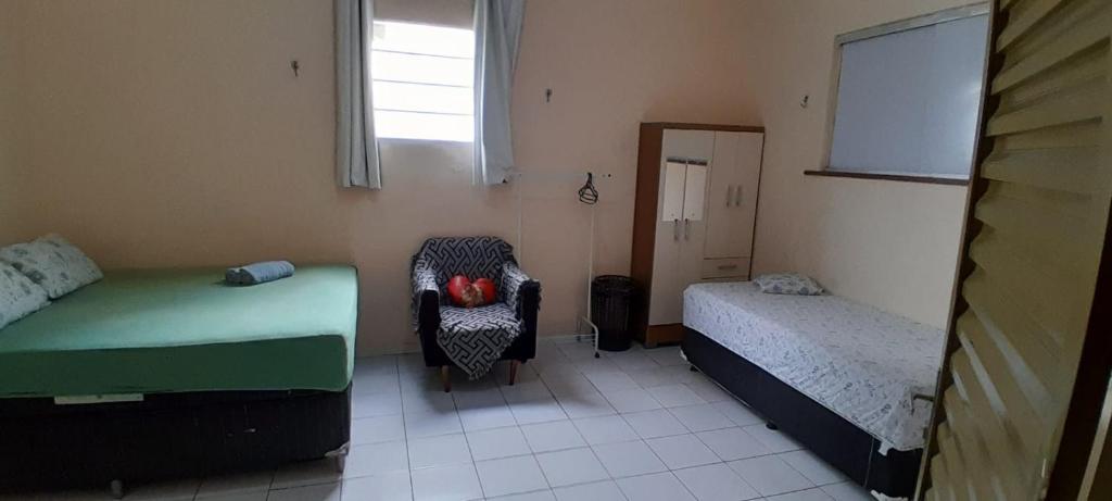 a room with two beds and a chair and a mirror at Apto em São Bráz in Belém