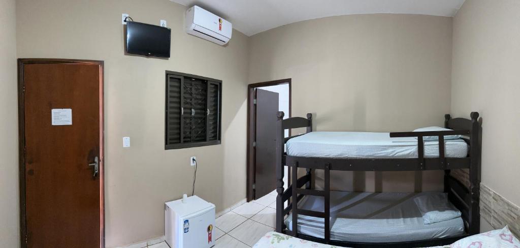a room with two bunk beds and a tv on the wall at Pousada Colorado in Olímpia
