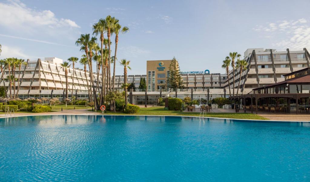 a large blue swimming pool in front of a building at Ilunion Islantilla in Islantilla