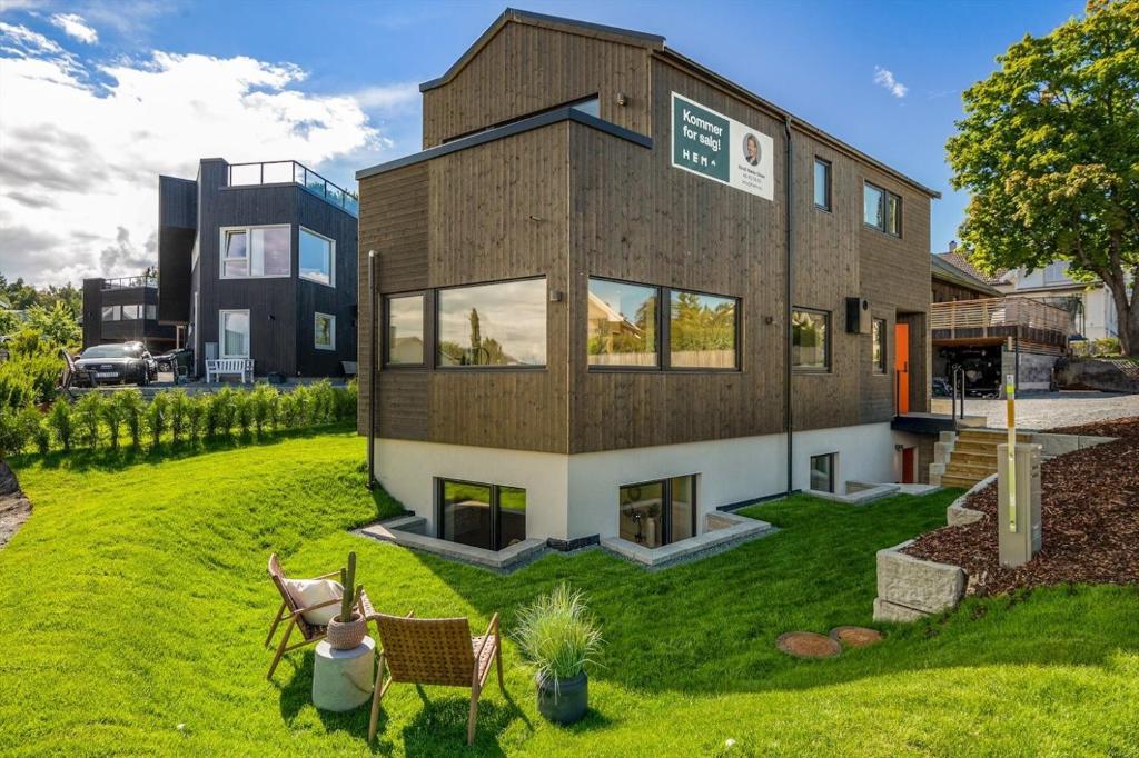 a house with a green yard with two chairs at Nytt funkishus - 15 minutter fra ski-VM i Granåsen in Trondheim