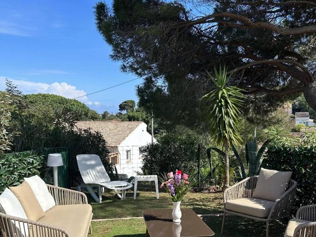 a yard with chairs and a table with a vase of flowers at Appartement 2 Chambres avec Climatisation et Jardin, à 400m de la Plage - Les Issambres - FR-1-768-72 in La Garonnette-Plage