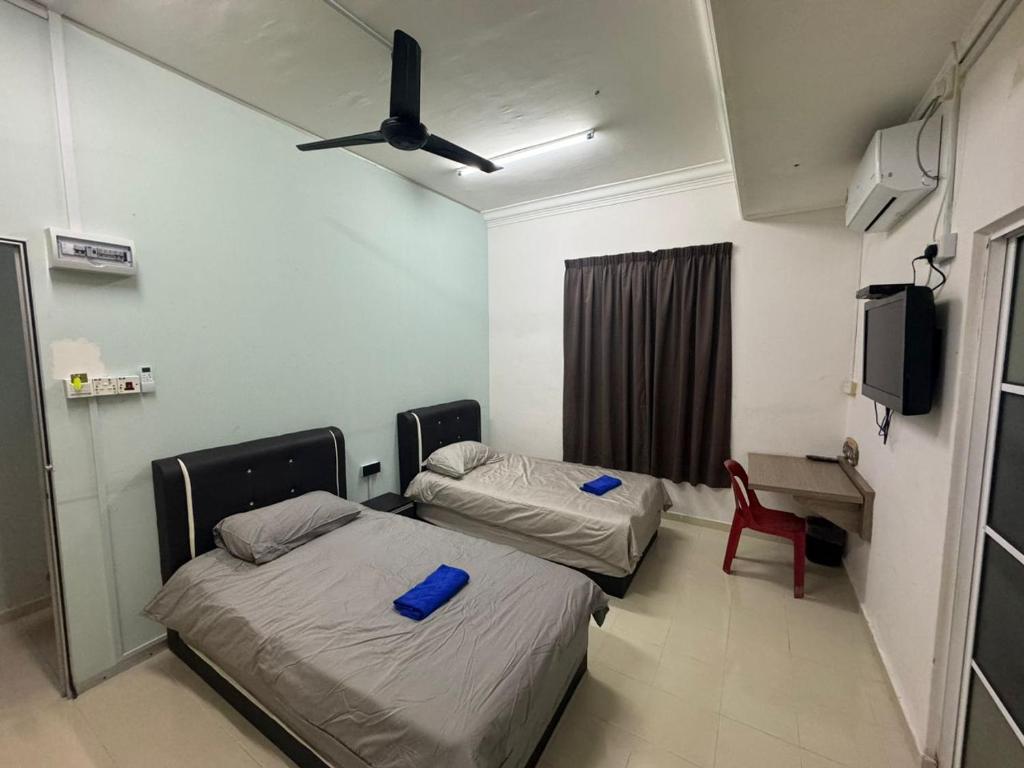 um quarto de hospital com duas camas e uma televisão em MOMO GUEST HOUSE em Kuala Terengganu
