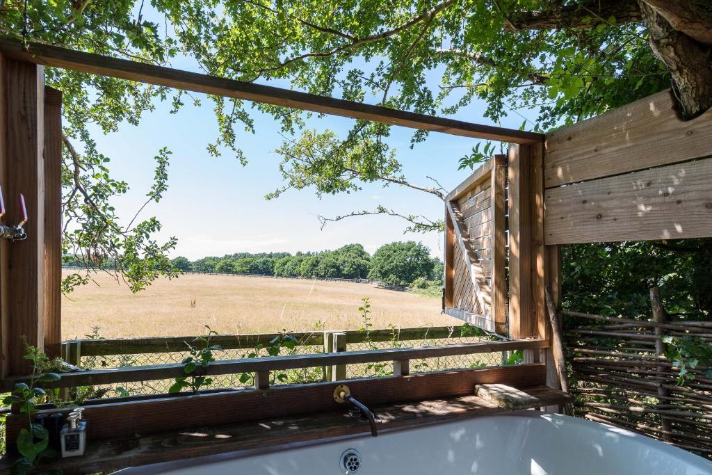 uma banheira com vista para um campo através de uma janela em Cabin Westerlands em Selham