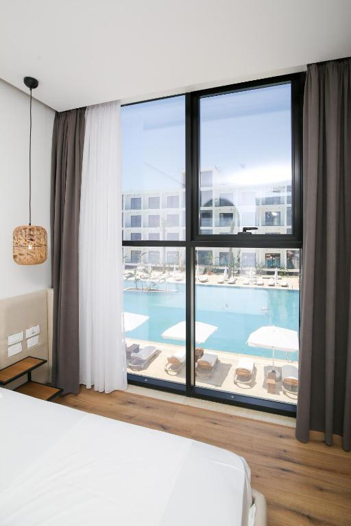 ein Schlafzimmer mit einem großen Fenster und einem Pool in der Unterkunft Oricon Coast Luxury Resort in Orikum