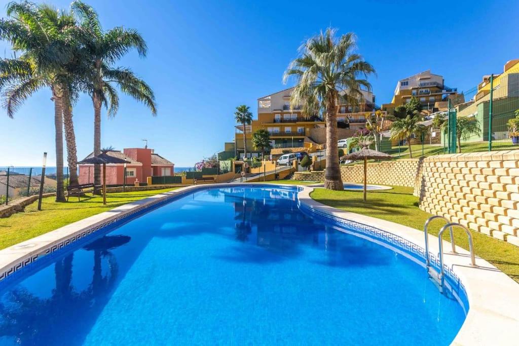 une grande piscine avec des palmiers et des condos dans l'établissement Costa Verde, à Finestrat