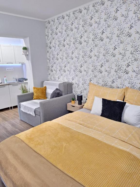 a bedroom with a bed and a couch and a kitchen at Várfal apartman in Eger