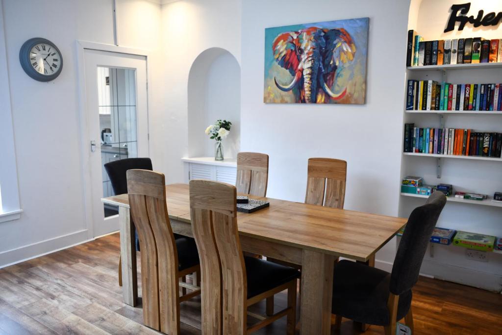 uma sala de jantar com uma mesa de madeira e cadeiras em The Prestwick Pad em Prestwick