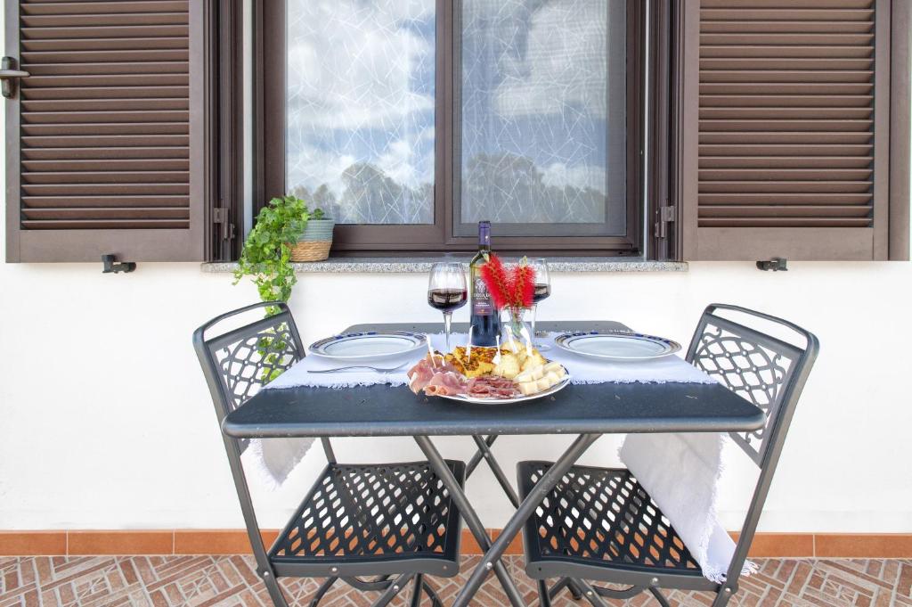 - une table avec deux chaises et une assiette de nourriture et de vin dans l'établissement Casa Vacanza Baratz 2, à Alghero