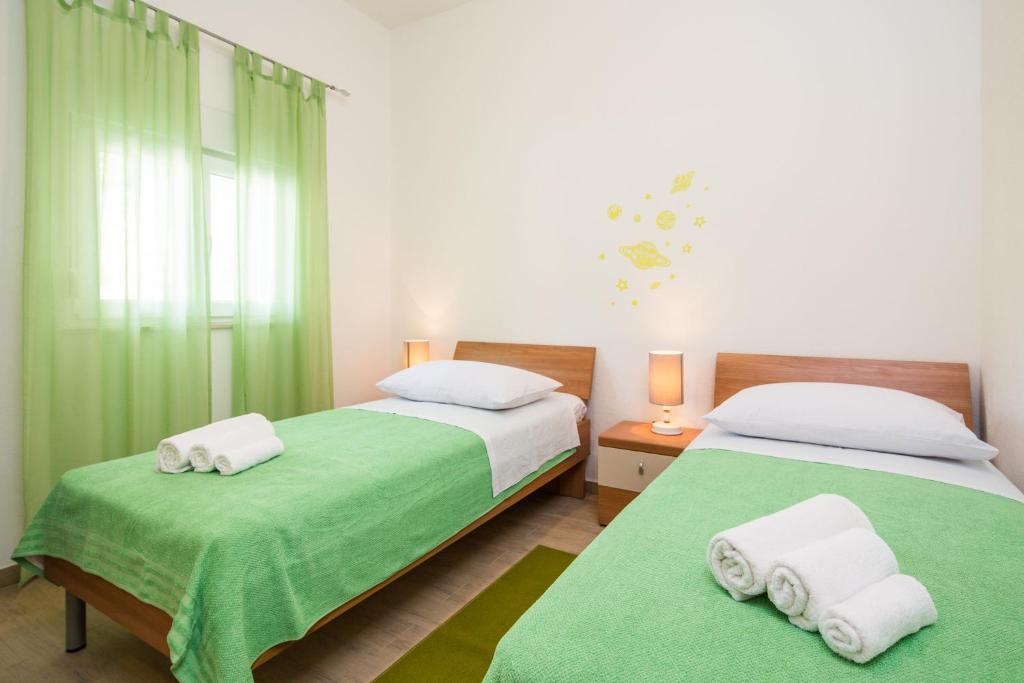 2 camas en un dormitorio con sábanas verdes y toallas en Apartment with private swimming pool, en Podstrana
