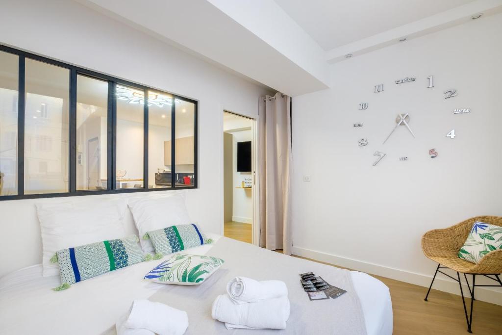 a white bedroom with a large clock on the wall at Appartement promenade des anglais in Nice