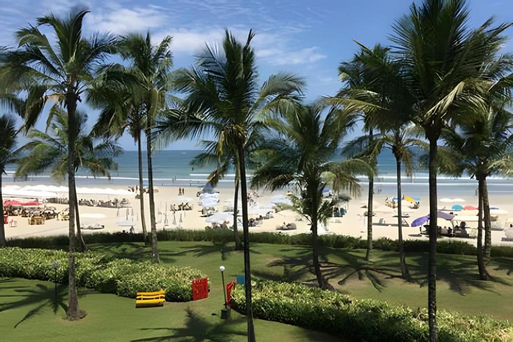 a view of a beach with palm trees and the ocean at Riviera: M4 Giardino 44A, frente Praia, 4Dorms, 3Banh, 2Gar, Varanda Gourmet com Churrasqueira in Riviera de São Lourenço