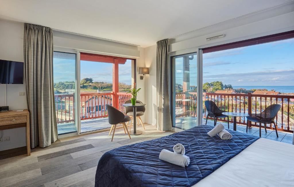 a bedroom with a bed and a view of the ocean at Hôtel Prestige Odalys Erromardie in Saint-Jean-de-Luz