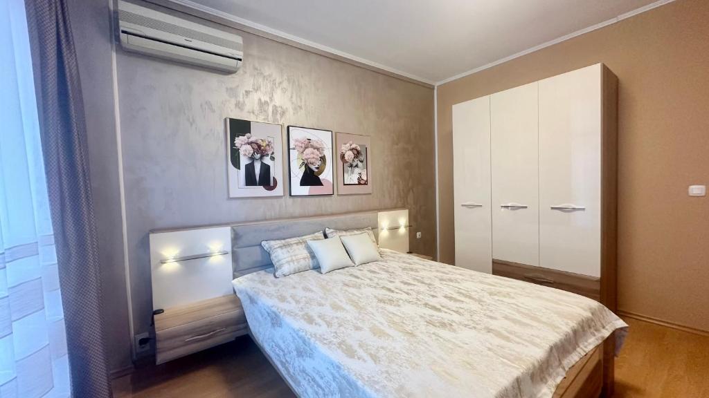 1 dormitorio con cama y pared con cuadros en Bratanov Flower Street Apartment, en Sunny Beach