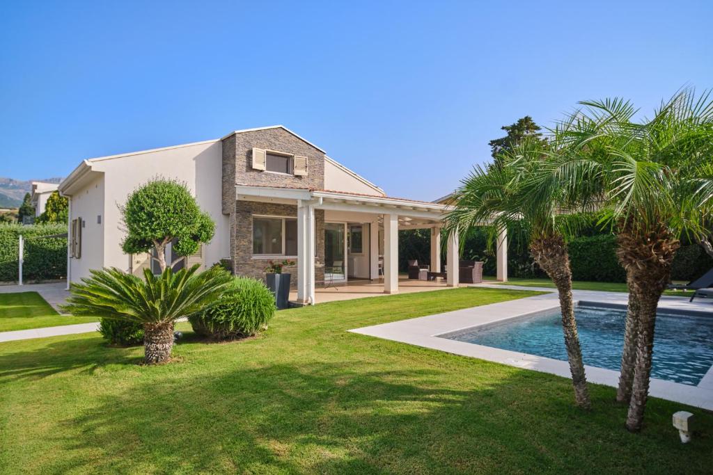 a house with a swimming pool and palm trees at Villa Sicilia in Lascari