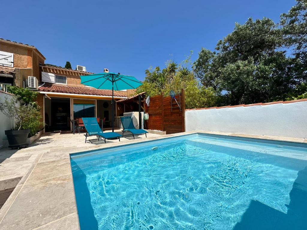 - une piscine avec 2 chaises et un parasol dans l'établissement Mazet provencal climatisé avec piscine privée pour 4 pers Domaine privé, à La Londe-les-Maures