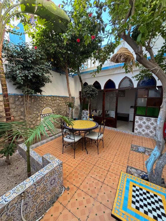 un patio con mesa y sillas frente a una casa en CampSurf Morocco, en Tamraght Ouzdar