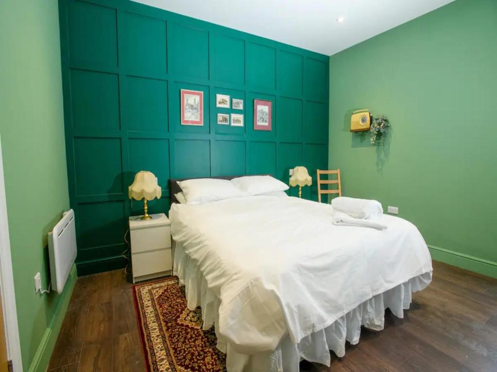 a bedroom with a large white bed with a green wall at Pass the Keys Traditional room Tavmar Apartments in Lincoln