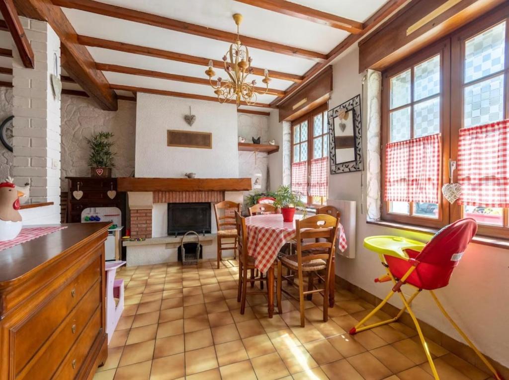 eine Küche mit einem Tisch und Stühlen sowie einem Kamin in der Unterkunft La Marquisienne avec jardin in Marquise