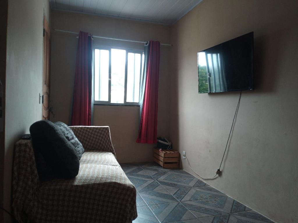 uma sala de estar com um sofá e uma televisão em Casa de Temporada em São Pedro da Aldeia