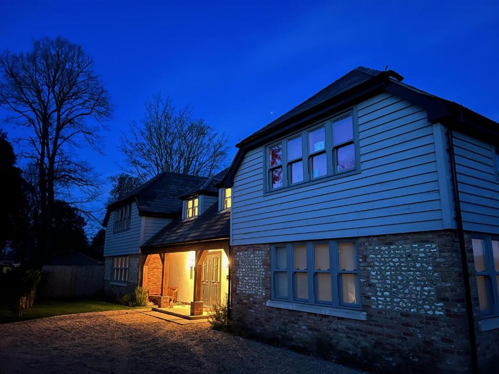 a house with its lights on at night at Flint House, Rew Lane, Chichester in Lavant